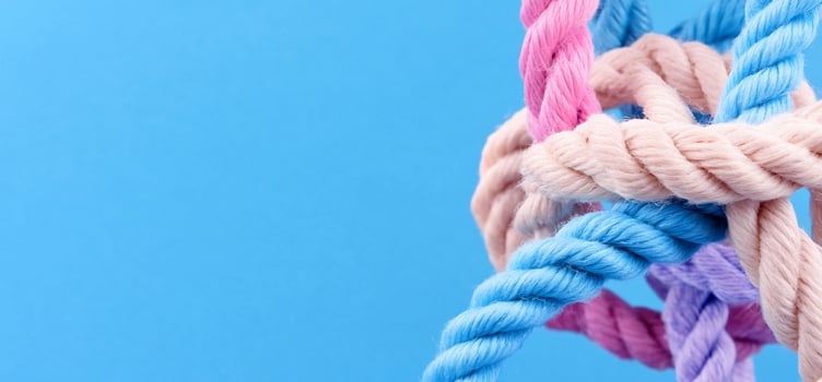 Intertwined pastel ropes on blue background close up photo