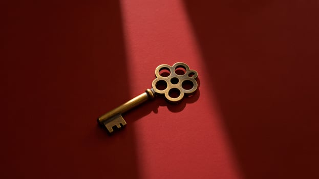 Antique skeleton key resting on a red background, featuring intricate designs and a unique shape. photo