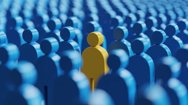 A yellow figure stands out among a crowd of blue figures, symbolizing individuality and uniqueness. photo