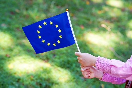 Little girl hands hold EU flag on a green field photo