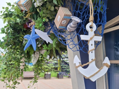 Nautical decor with white anchor and blue starfish amidst green foliage photo