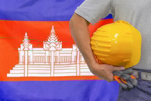 Hand of worker and yellow hard-hat on background flag of Cambodia photo