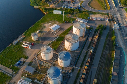 Sunset aerial view of cylindrical storage tanks, pipelines, rail tracks, freight cars, and a road near a body of water in Riga, Latvia. photo