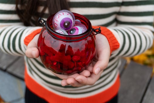 Woman holding red jar with toy eyeballs for halloween decoration photo