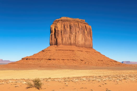 Monument Valley's majestic butte rises dramatically against the stark blue sky on a sunny day photo