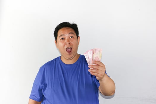 Asian man holding money and surprised photo