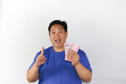 Asian man holding money and pointing finger photo