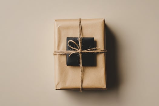 Two gifts wrapped in kraft paper and tied with string sitting on a neutral surface photo