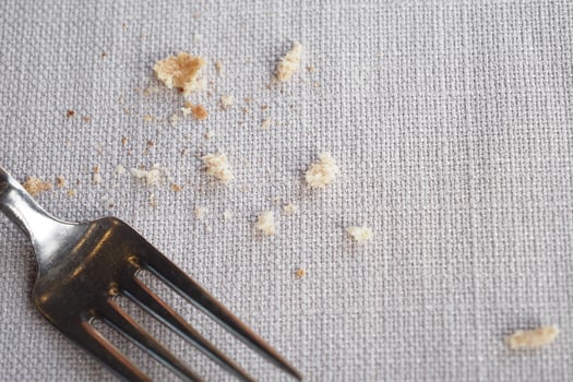 Crumbs on a tablecloth beside a fork after a meal photo