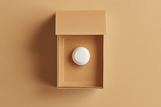 Top view shows a white sphere within a minimal brown box on tan backdrop photo