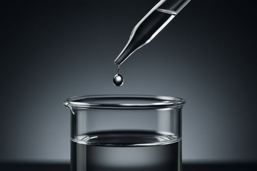 close up of a transparent liquid drop falling from pipette into glass beaker symbolizing precision cleanliness and scientific research in modern laboratory setting photo