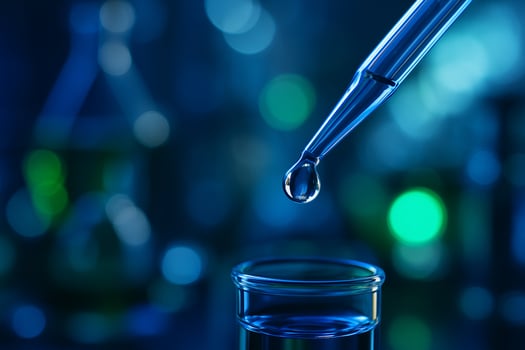 close up of a clear liquid droplet at the tip of a pipette with blurred blue and green laboratory background symbolizing precision and scientific innovation photo