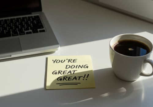 Sunlit Desk with 'You're Doing Great' Sticky Note, Coffee, and Laptop Shadows photo
