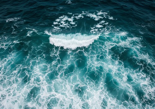 Aerial View of Deep Teal Ocean Waves with White Foamy Swirls and Sunlight Reflections photo