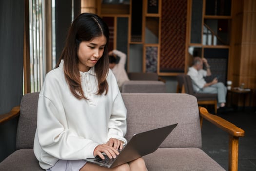 A young woman focused on her laptop in a stylish lounge, surrounded by modern decor and soft lighting. photo