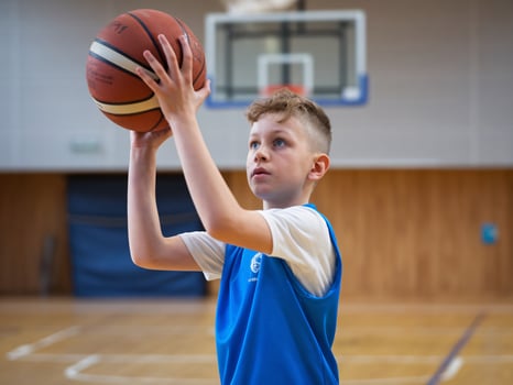 Young boy practicing basketball in a gym, showing focus and determination while aiming for the basket. photo