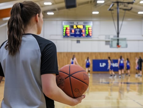 Female athlete holding a basketball, focusing on the game in a gymnasium setting. photo