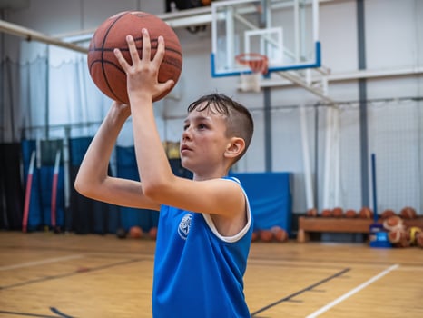 Young boy practicing basketball in a gym, focused on making a shot with determination. photo