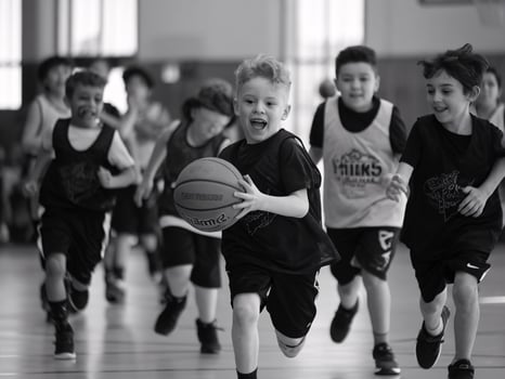 Excited young boy running with a basketball during practice, surrounded by teammates in a gym. photo