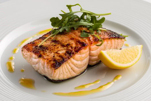 Grilled salmon fillet garnished with arugula and lemon on a white plate. photo