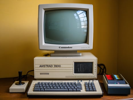 Vintage computer setup featuring an Amstrad 38010 and a classic monitor on a wooden desk. photo