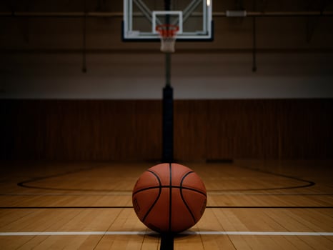 A close-up of an orange basketball on a hardwood court in a gymnasium, focused on the ball. photo
