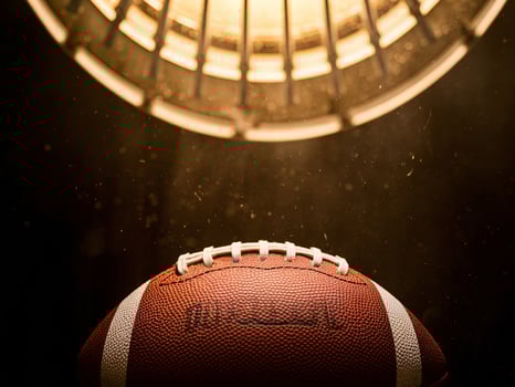 A close-up of a football illuminated by a bright overhead light, creating a dramatic scene. photo