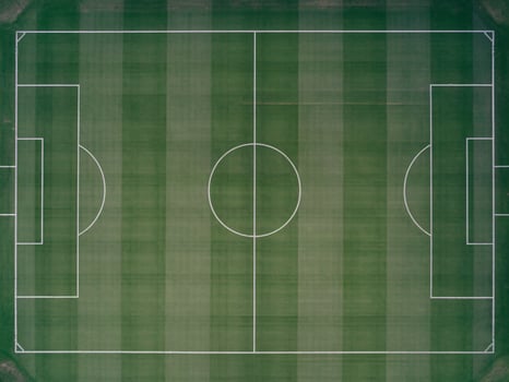 Aerial view of a pristine green soccer field with white markings and goal areas, showcasing a vibrant texture. photo