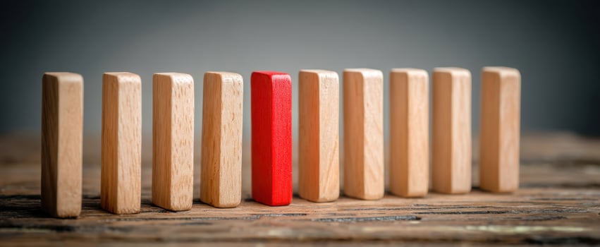 The Red Domino Standing Out Among the Wooden Group in a Motivational Scene photo
