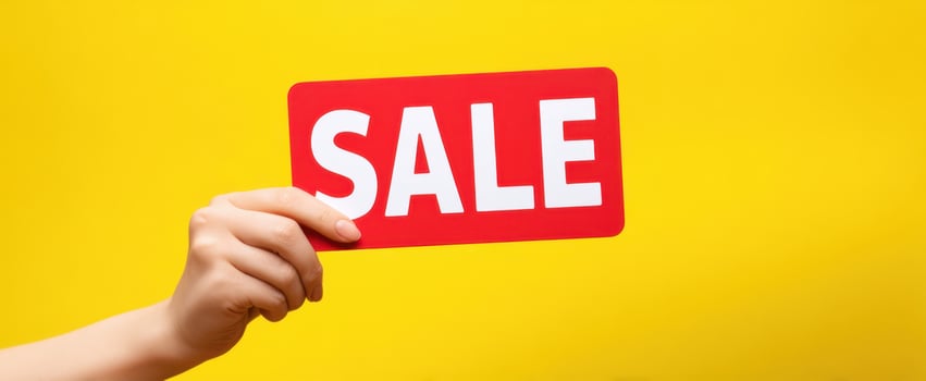 The bold red SALE sign held against a bright yellow background. photo