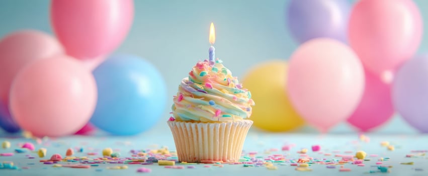 The colorful cupcake with candle surrounded by festive balloons and sprinkles. photo