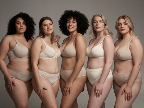 Five women of diverse body types and ethnicities posing confidently in beige lingerie. photo