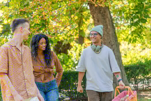 Happy Multicultural friends walking in the park, carrying picnic basket and enjoying leisure time photo