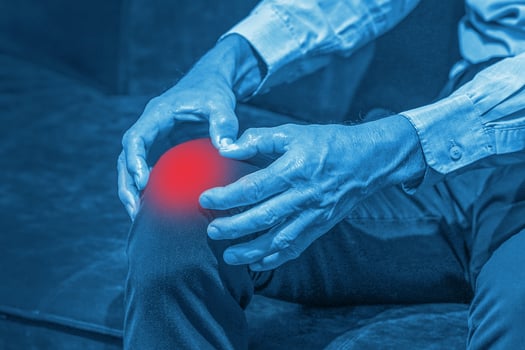 Elderly man with his hands on a painful knee joint photo