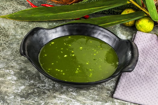 A bowl of green soup next to a bowl of green beans photo