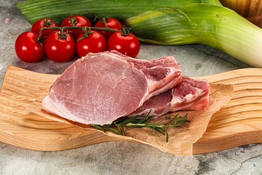 A cutting board with a piece of meat, tomatoes and corn photo