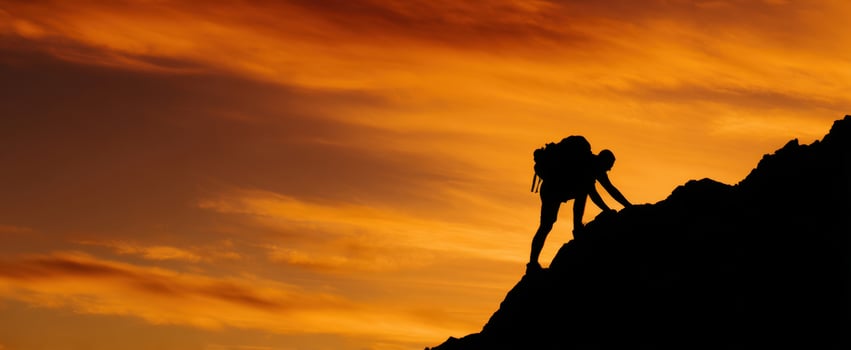 The climber conquering the rocky summit under a vibrant sunset sky. photo