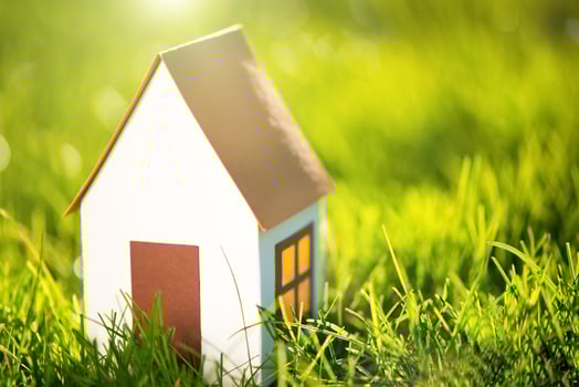 Paper home on green grass. Eco house concept photo