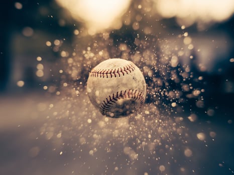 A baseball suspended in motion, surrounded by a burst of dust and light, creating a dynamic, energetic atmosphere. photo