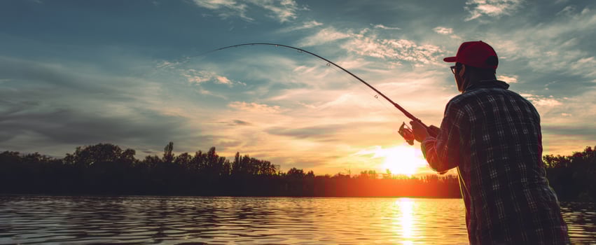 The fisherman casting his line during a serene sunset by the river. photo