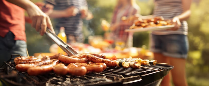 The grill sizzling with delicious sausages at a lively outdoor barbecue party. photo