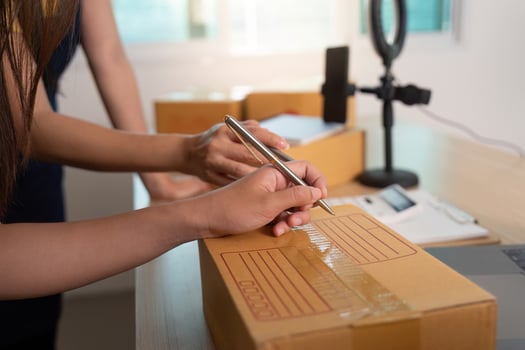 E-commerce. Woman labeling a package while preparing it for shipment. photo