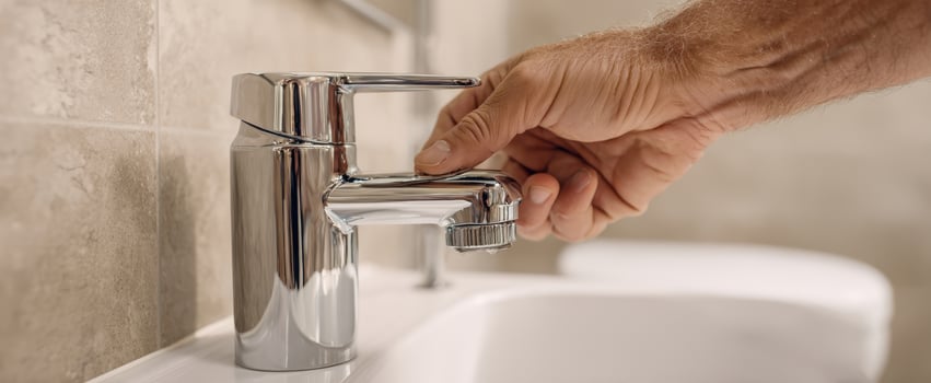 The modern faucet being turned on in a stylish bathroom setting. photo