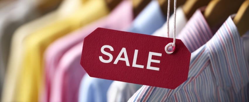 The vibrant sale tag hanging between colorful shirts in a retail store. photo