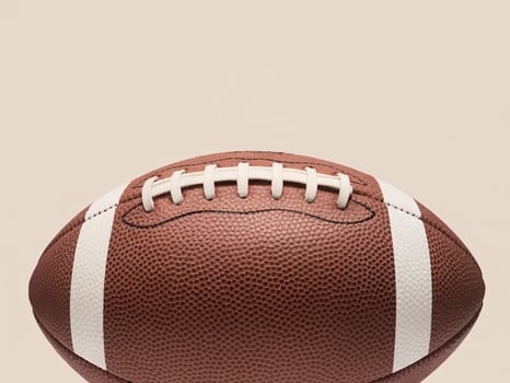 Close-up of a brown football with white stripes on a neutral background. photo