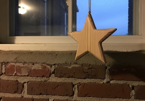Wooden Star Ornament Hanging by Window on Brick Wall photo