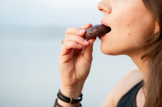 Close-up of woman biting a chocolate candy, enjoying sweet t photo