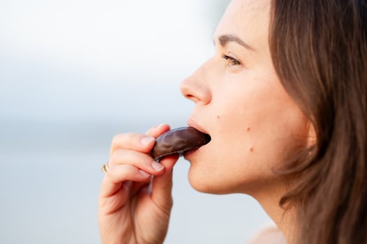 Close-up of woman biting a chocolate candy, enjoying sweet tre photo
