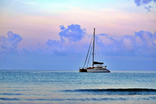A sleek sailing vessel anchored in calm seas awaits its next voyage as twilight colors illuminate the sky. photo