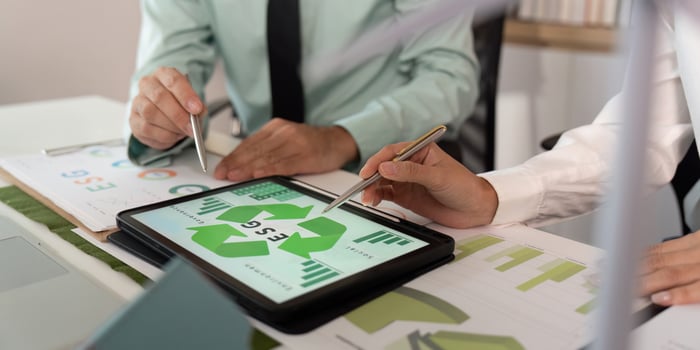 ESG Strategy Discussion. Professionals analyzing sustainability metrics on tablet. photo